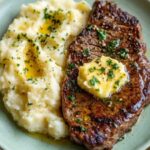 Garlic butter steak and mashed potatoes recipe served on a green plate.
