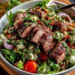 Chimichurri steak salad bowl served in a white ceramic bowl with fresh herbs.