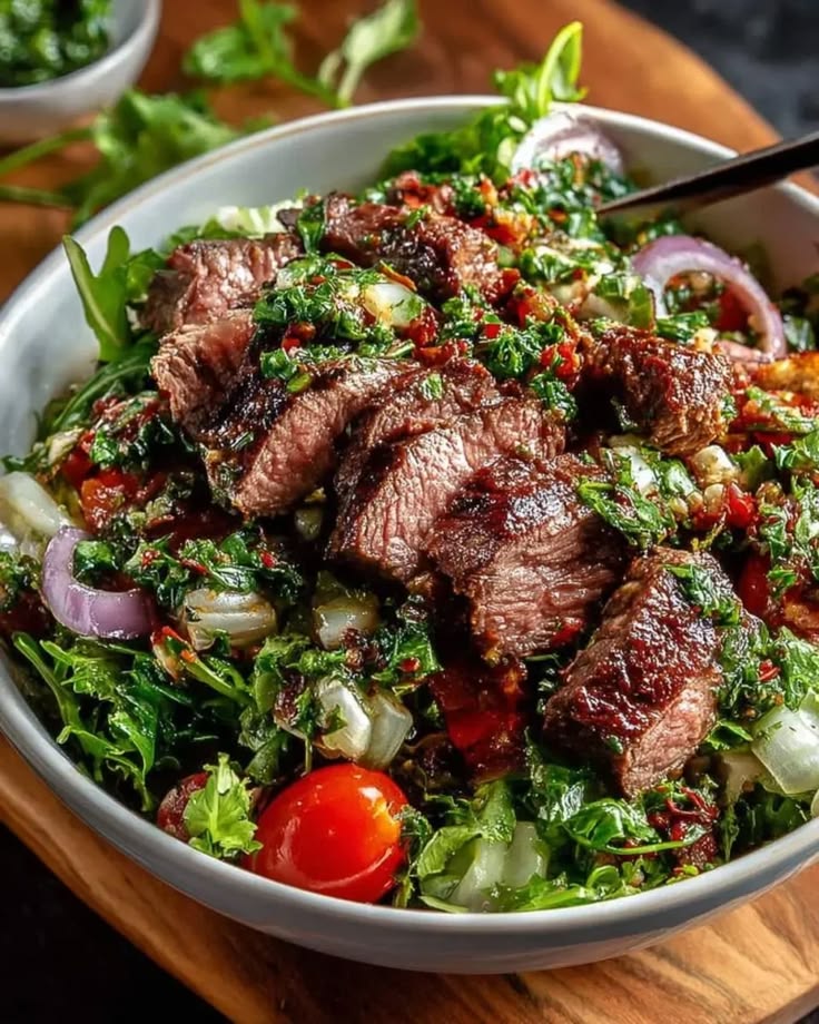 Chimichurri steak salad bowl served in a white ceramic bowl with fresh herbs.