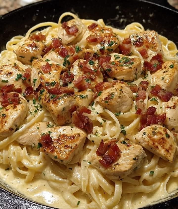 A skillet filled with creamy chicken bacon pasta topped with fresh parsley.