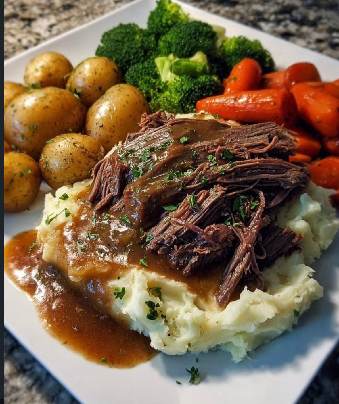 Classic Sunday Pot Roast served over mashed potatoes with sides.
