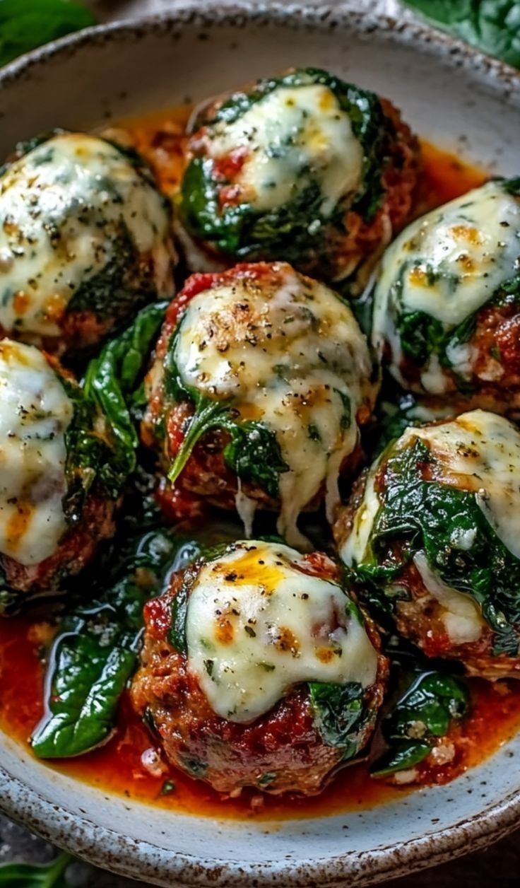 Easy cheesy baked meatballs with spinach and marinara recipe sizzling in a serving bowl.